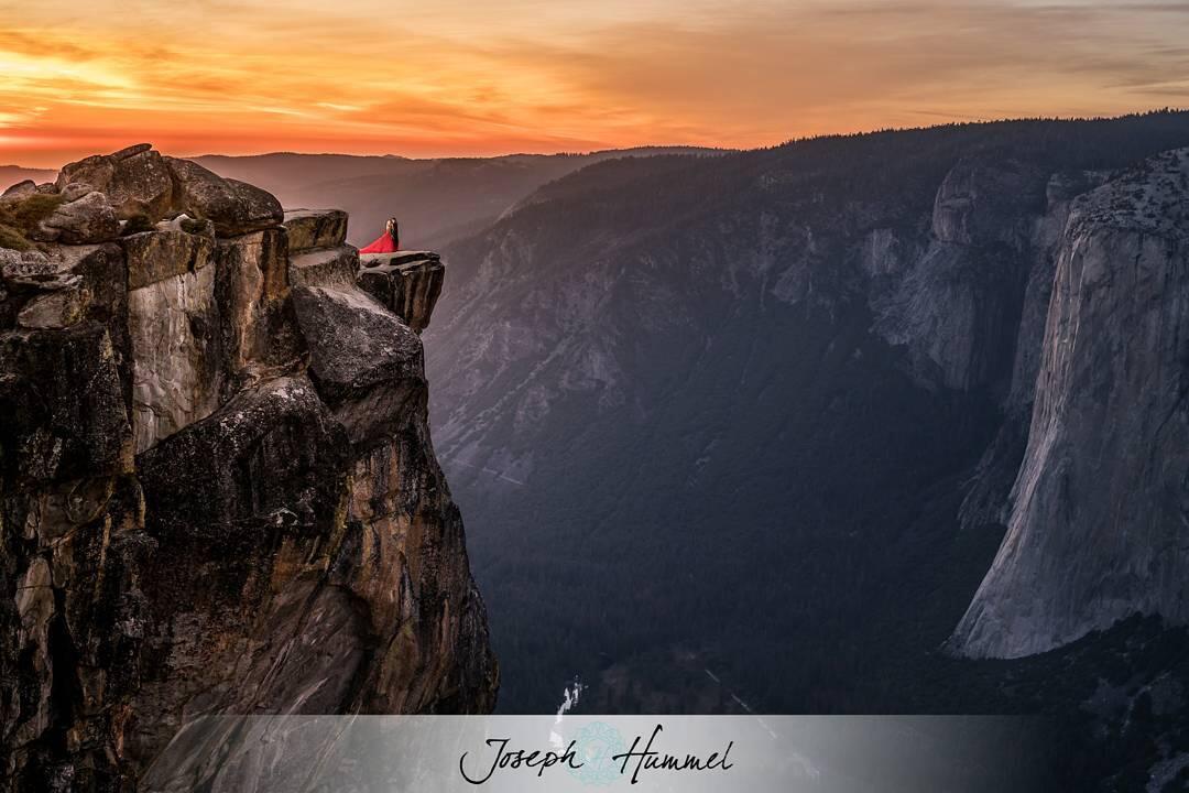 Adventure elopement photography featuring a couple posing on top of a cliff with a sunset sky backdrop