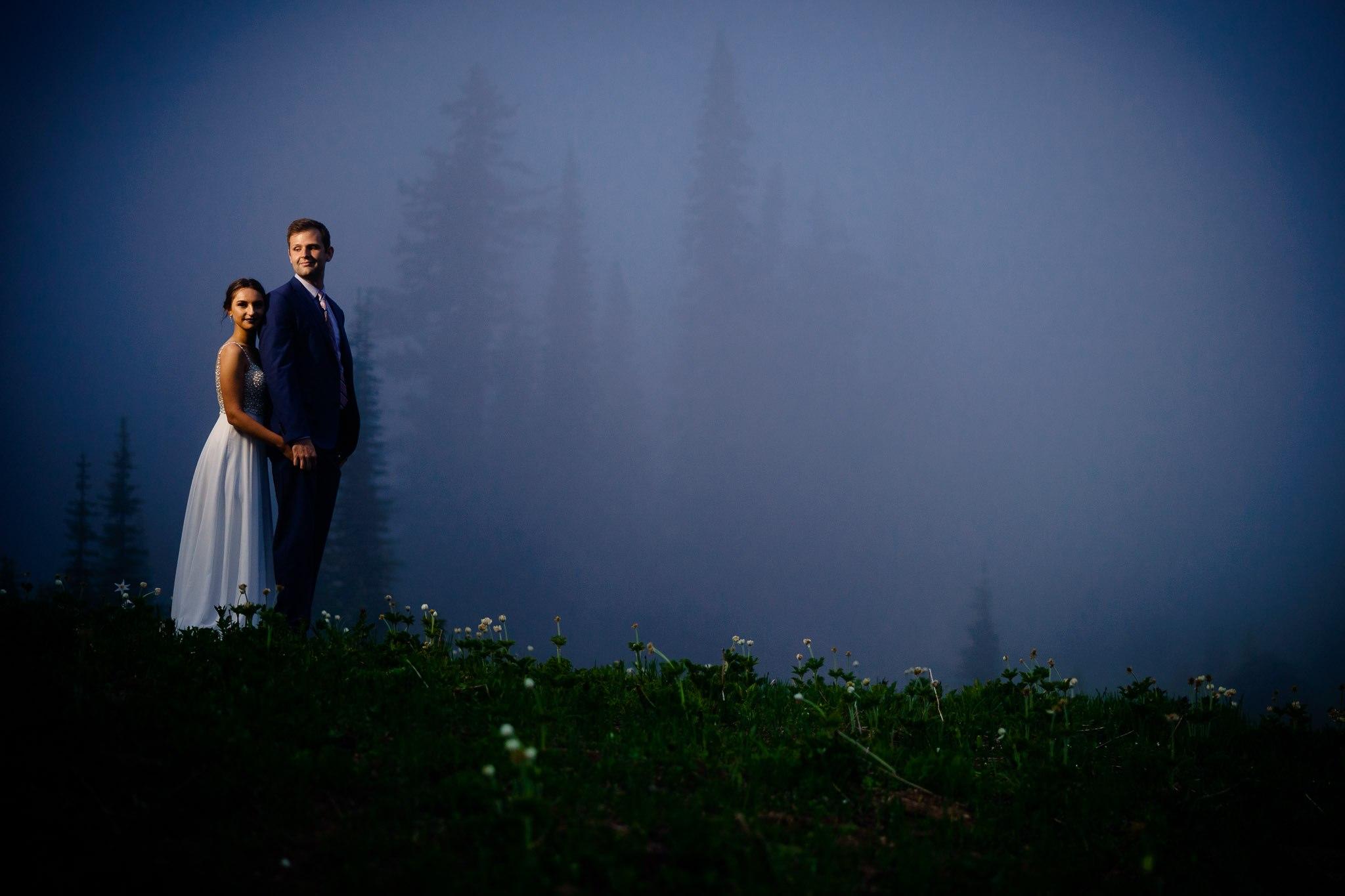 A foggy evening wedding shot with the couple standing on a hill. Edited by ShootDotEdit. 