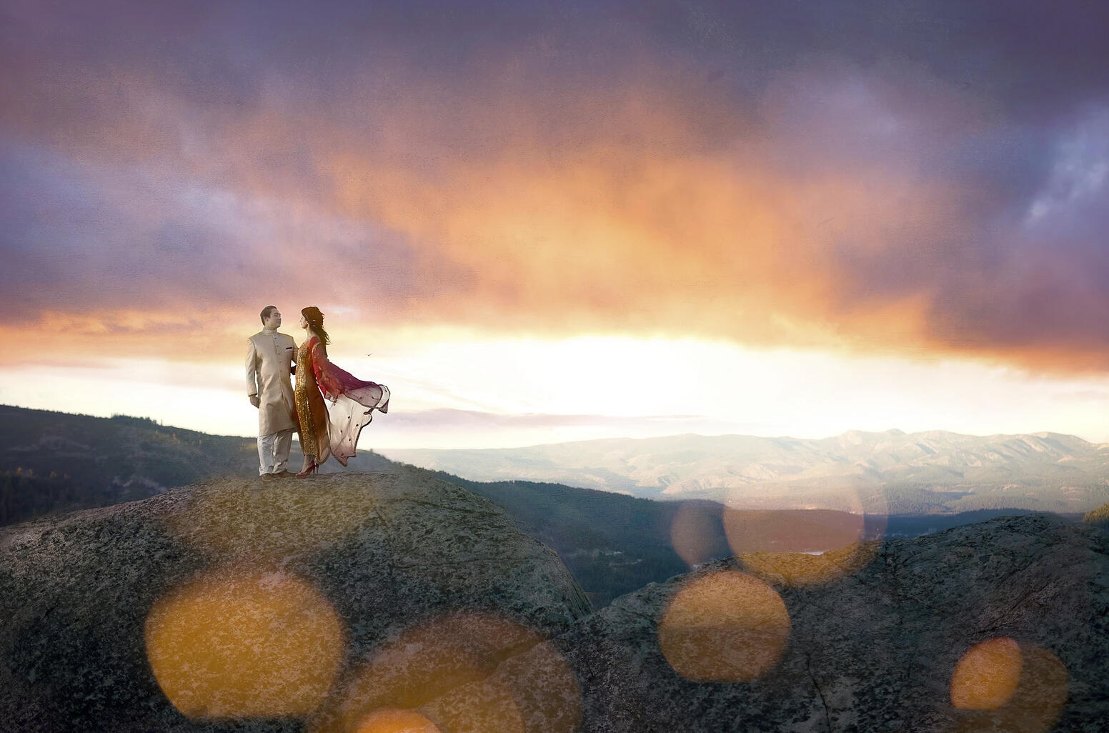 couple on rock ledge at sunset