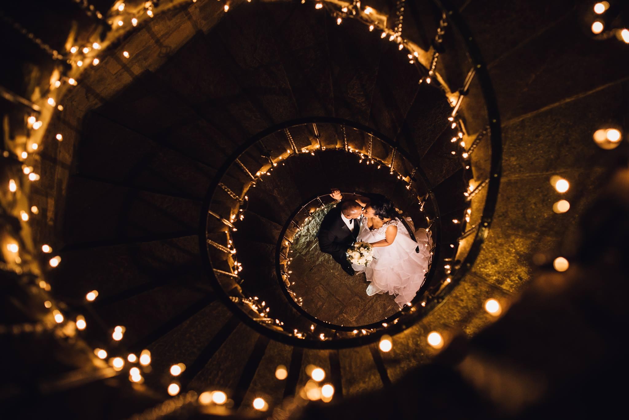 spiral staircase with twinkle lights and couple kissing at bottom