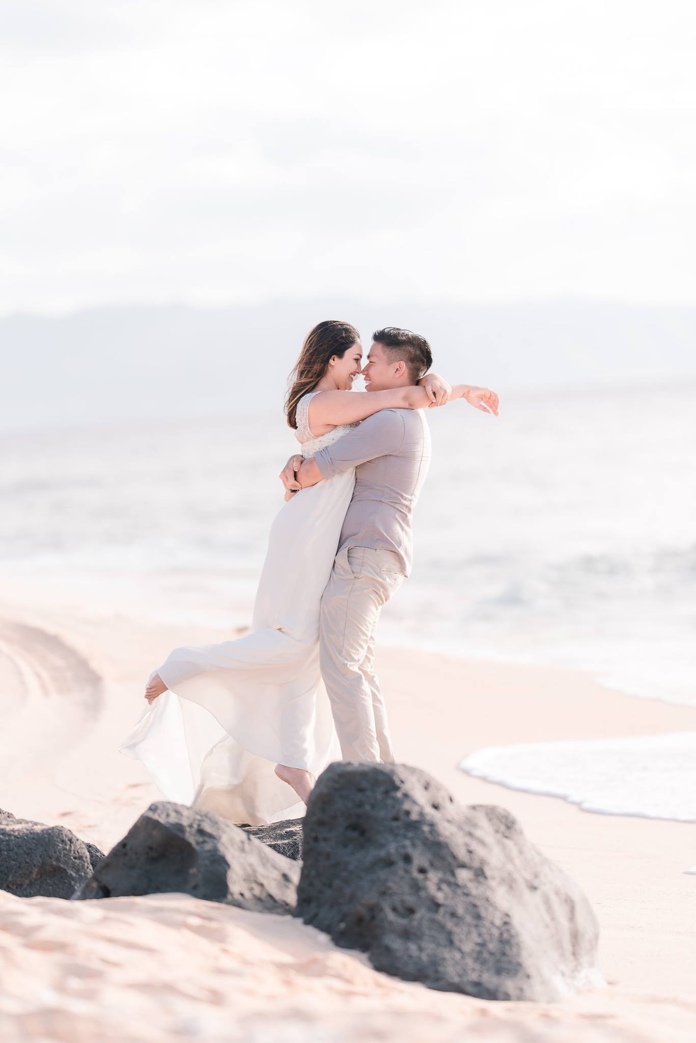 A couple holding each other as they pose by the beach