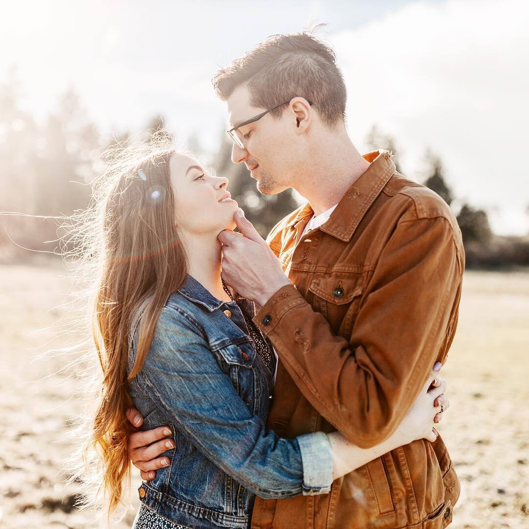 engagement session with woman in jean jacket and man in brown jacket in sunflare