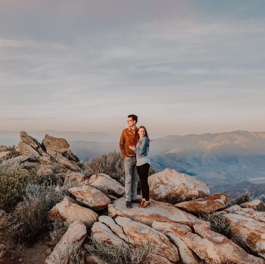 man and woman standing on rocks with a canyon behind them