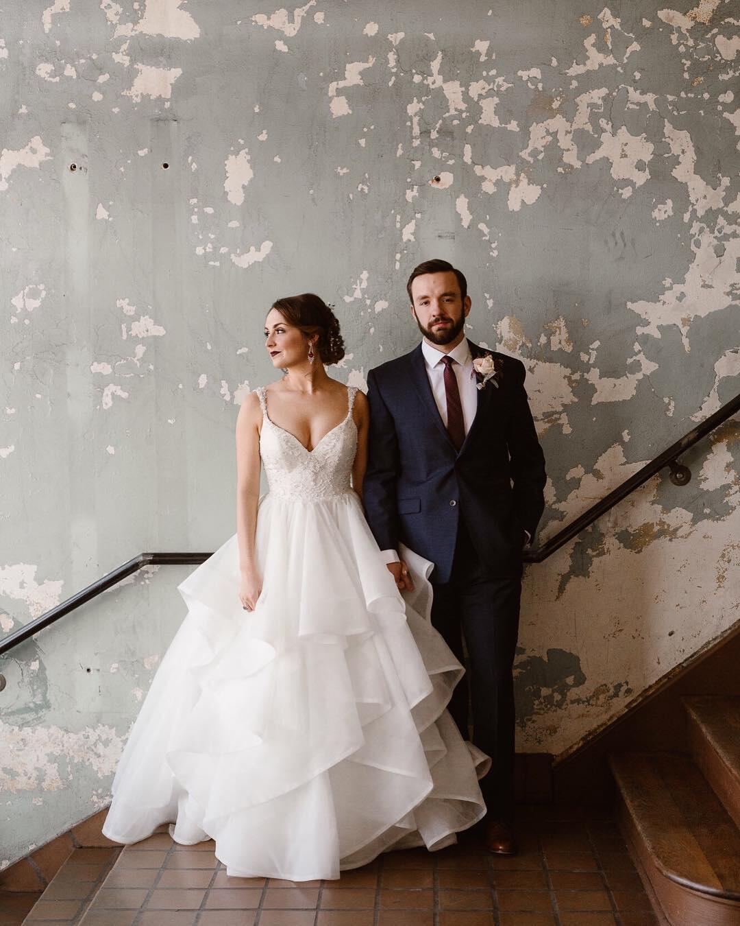 couple standing against wall with paint peeling 