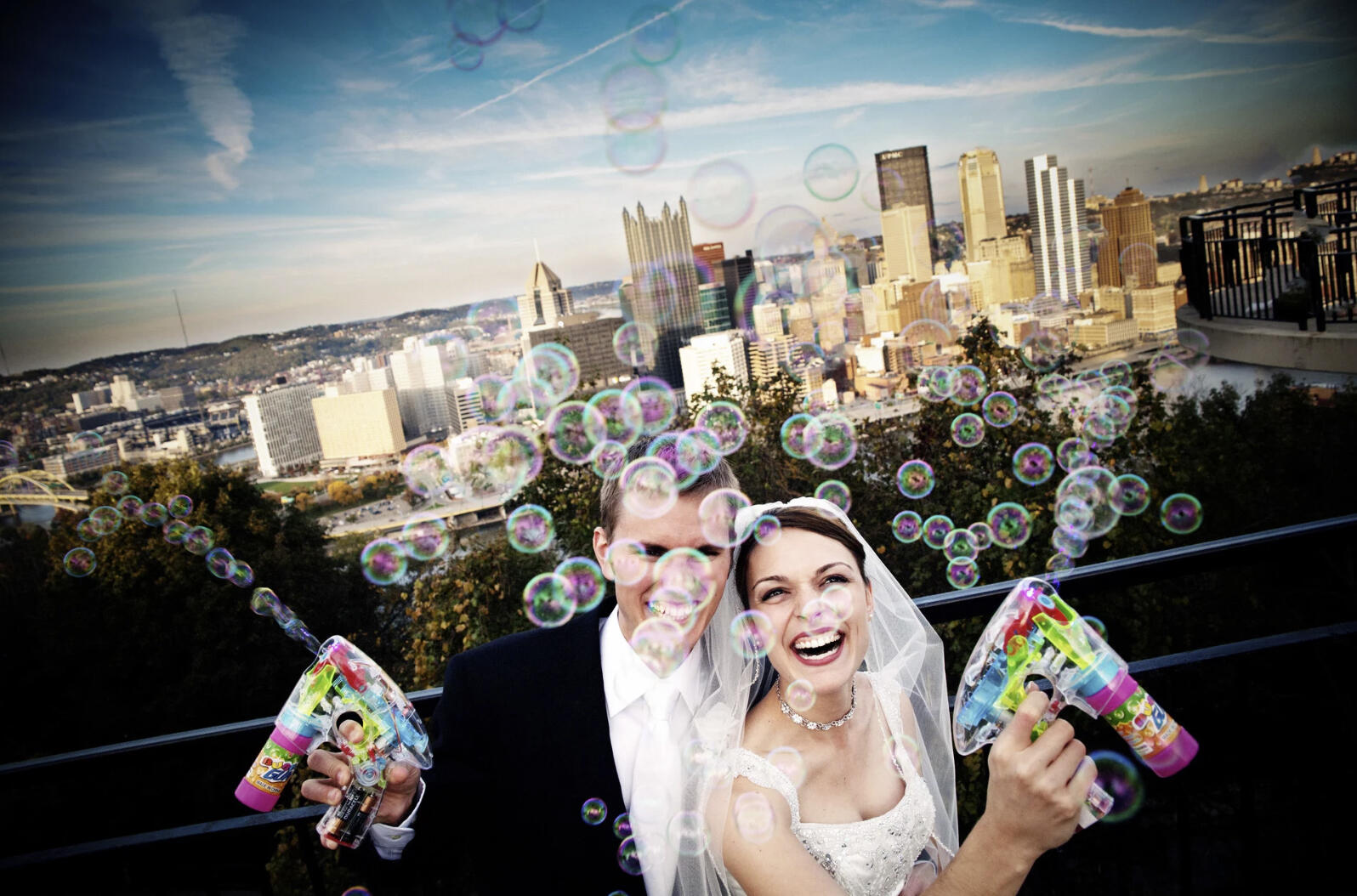 Candid image of a bride and groom posing with soap bubble guns