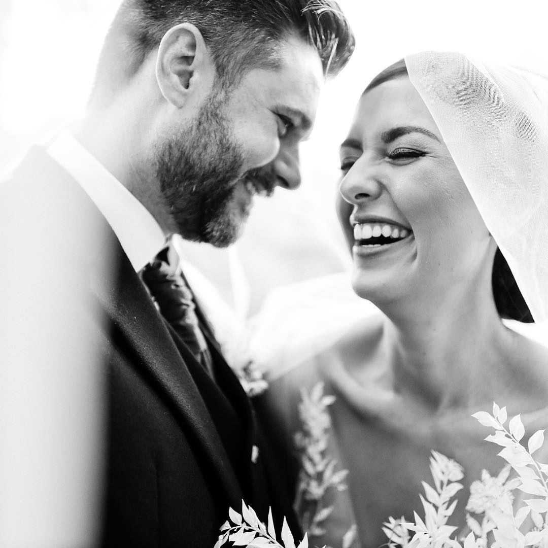 a monochrome portrait of a bride and groom under the bride's wedding veil 