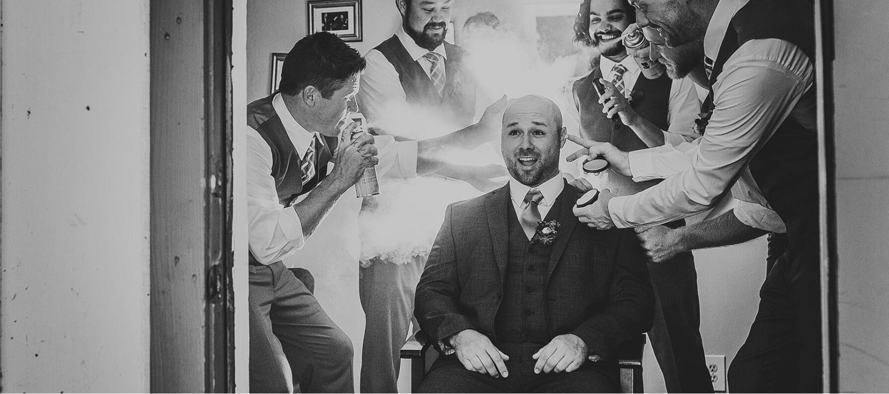 groom getting hairsprayed by groomsmen