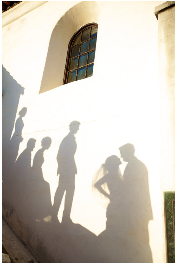 shadows of a bride and groom and the bridal party against a yellow colored wall