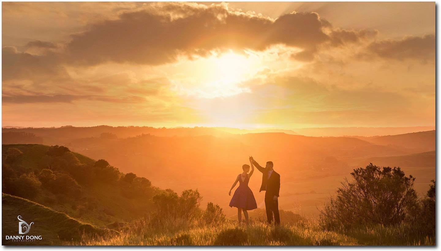 A couple posing for a twirl at sunset during an engagement session