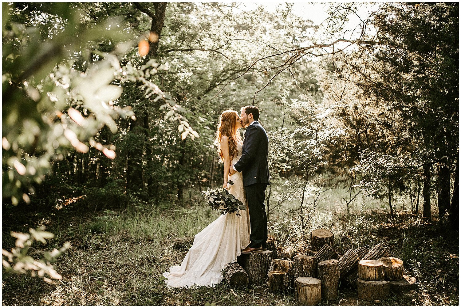 a newly married couple kissing each other in the middle of a forest