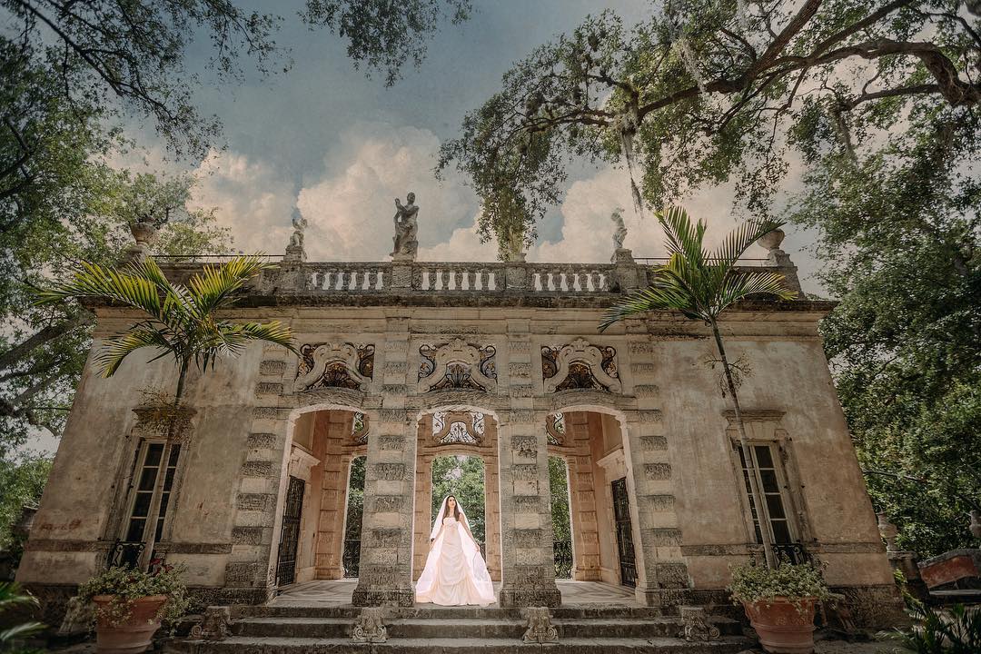 A wide-angle shot of a bride standing at the doorway of a beautiful wedding venue