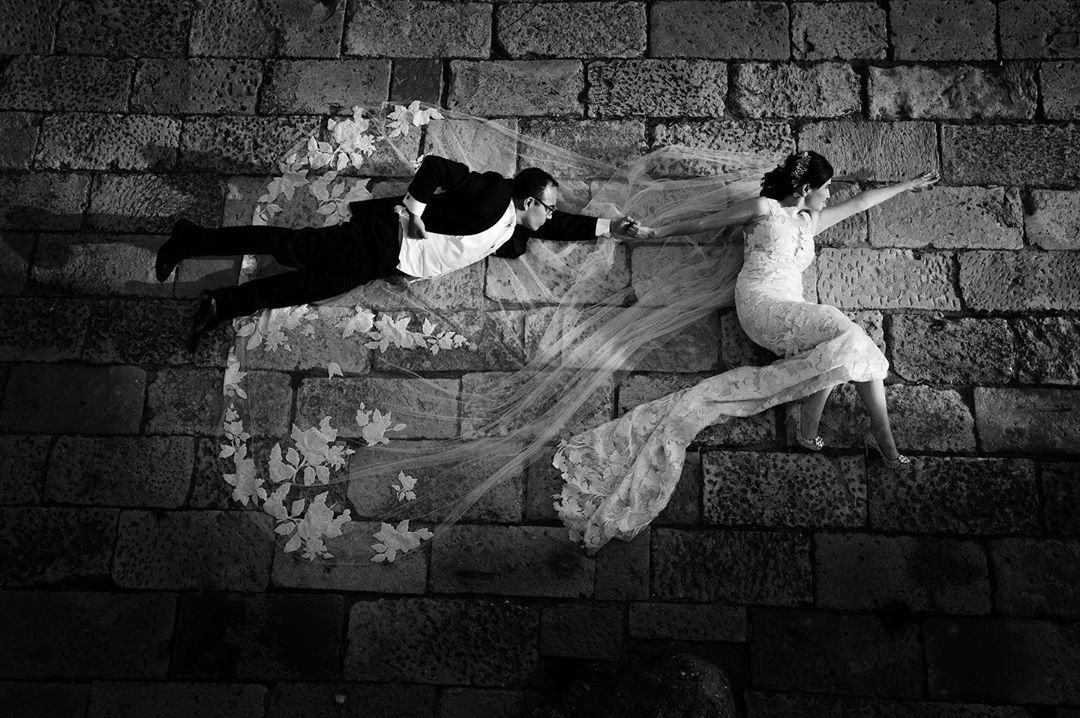 Black and white photograph of the bride and groom posing creatively as superheroes