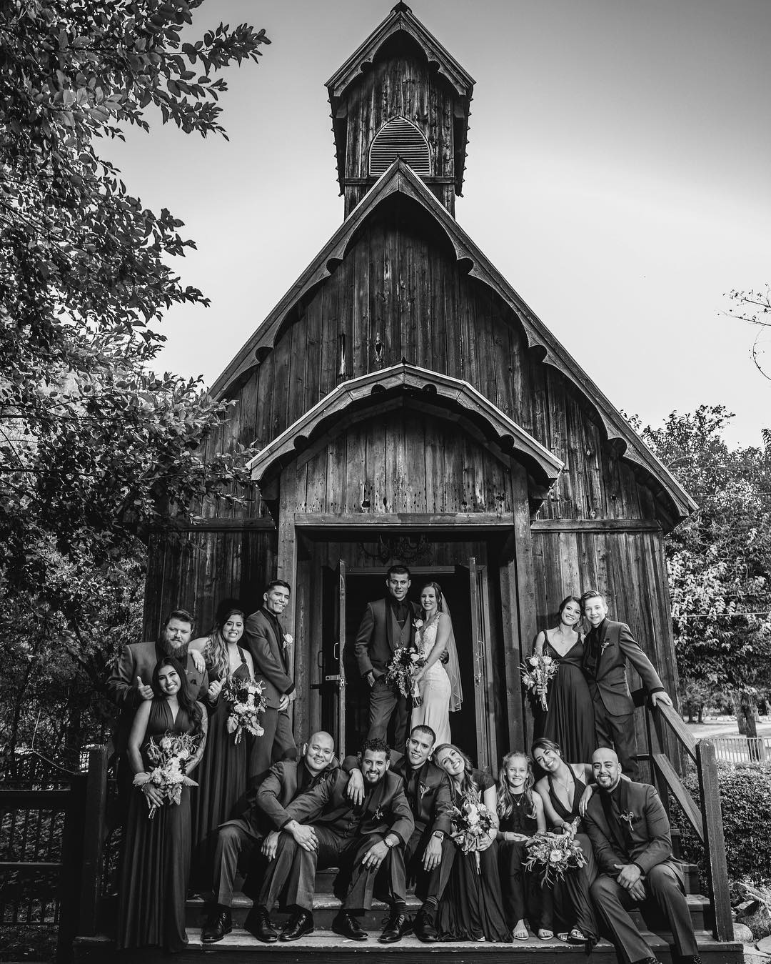 Black and white image of a couple and the bridesmaids and groomsmen posing at the entrance of a building