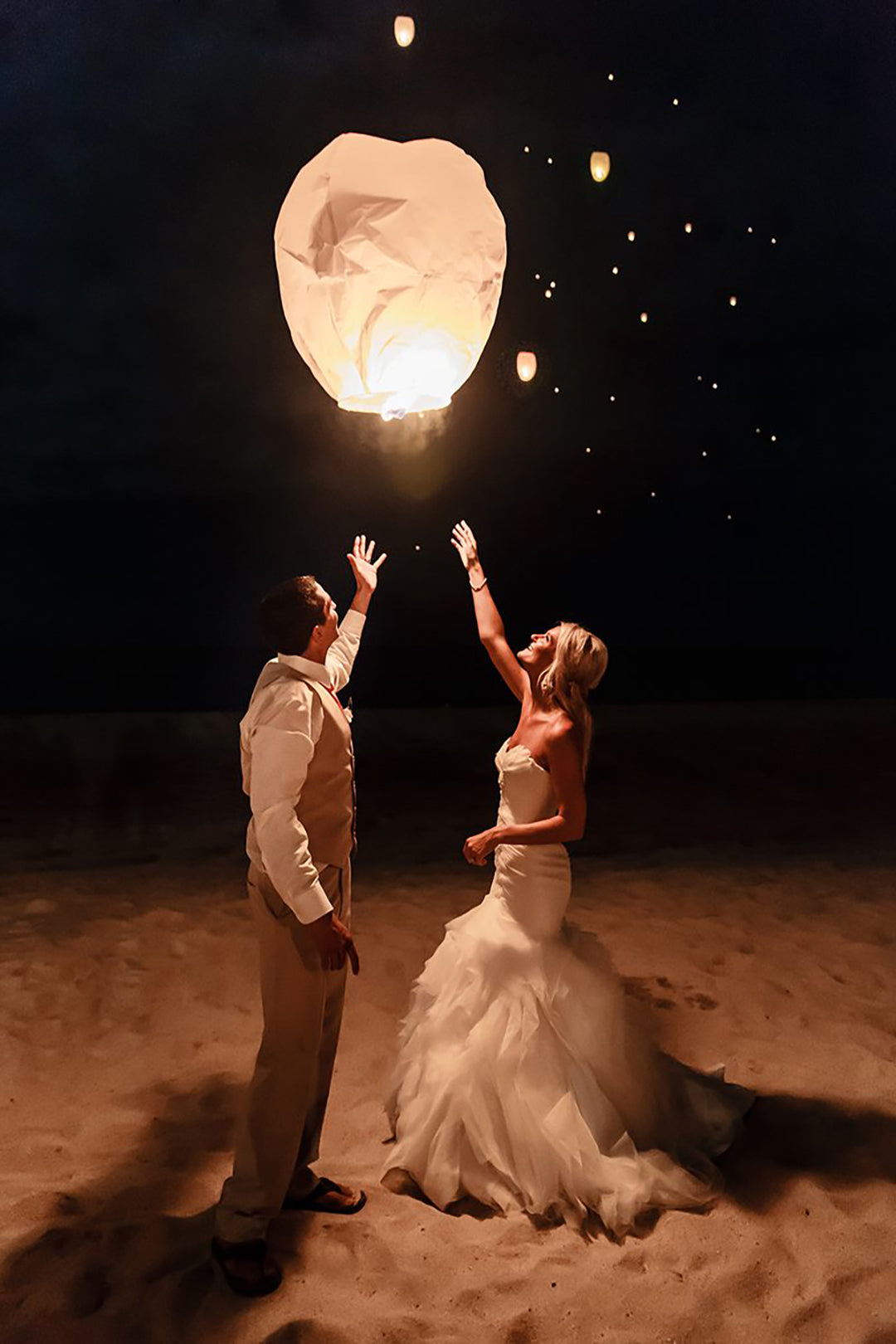 A couple in their wedding outfit release a sky lantern in the beautiful night sky