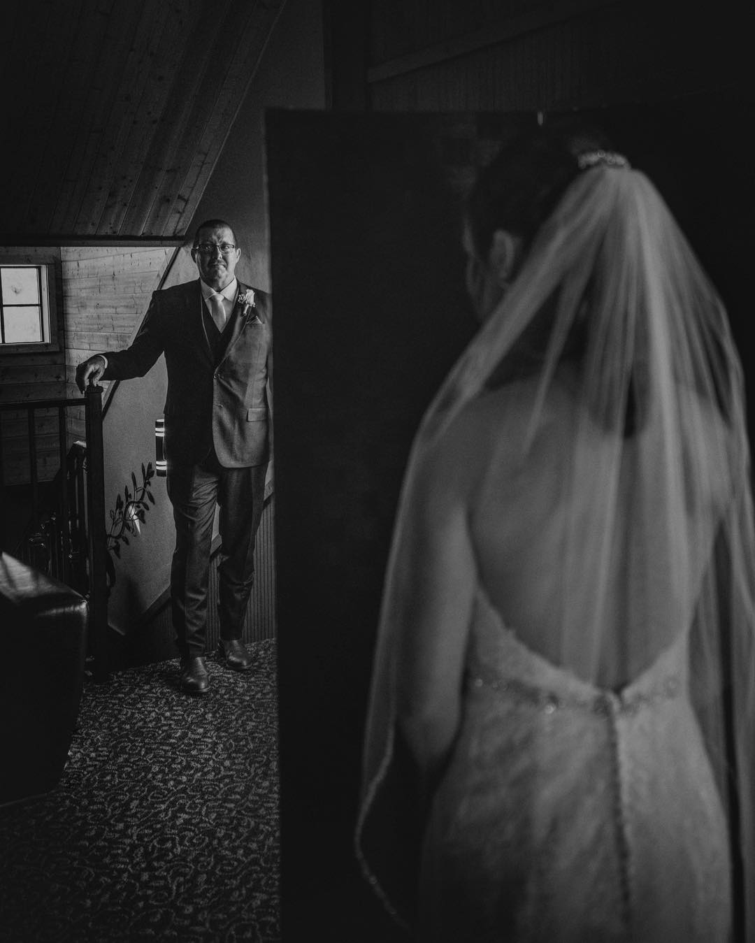 Over the shoulder shot of a bride looking at her father as he enters from the other side of the room