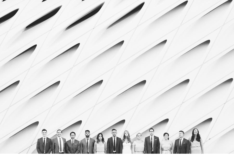 A monochrome of an image of bridesmaid and groomsmen posing in front of a wall