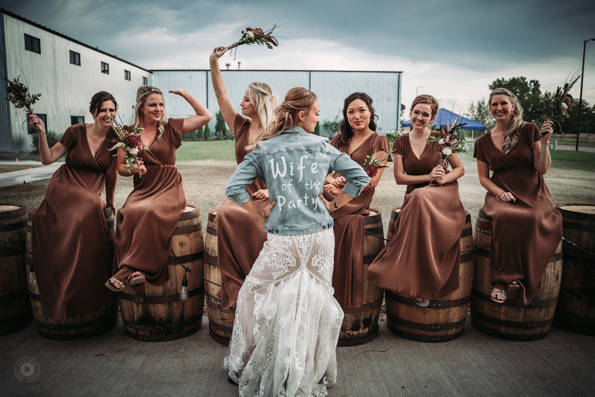 A bride posing with her bridesmaids wearing a denim jacket