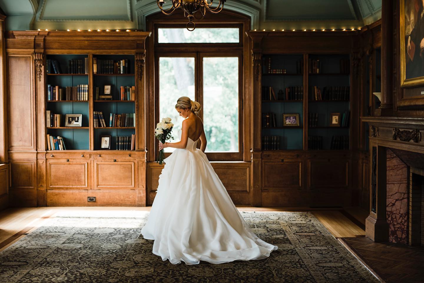 A portrait of a bride posing in front of a window in a vintage-themed room