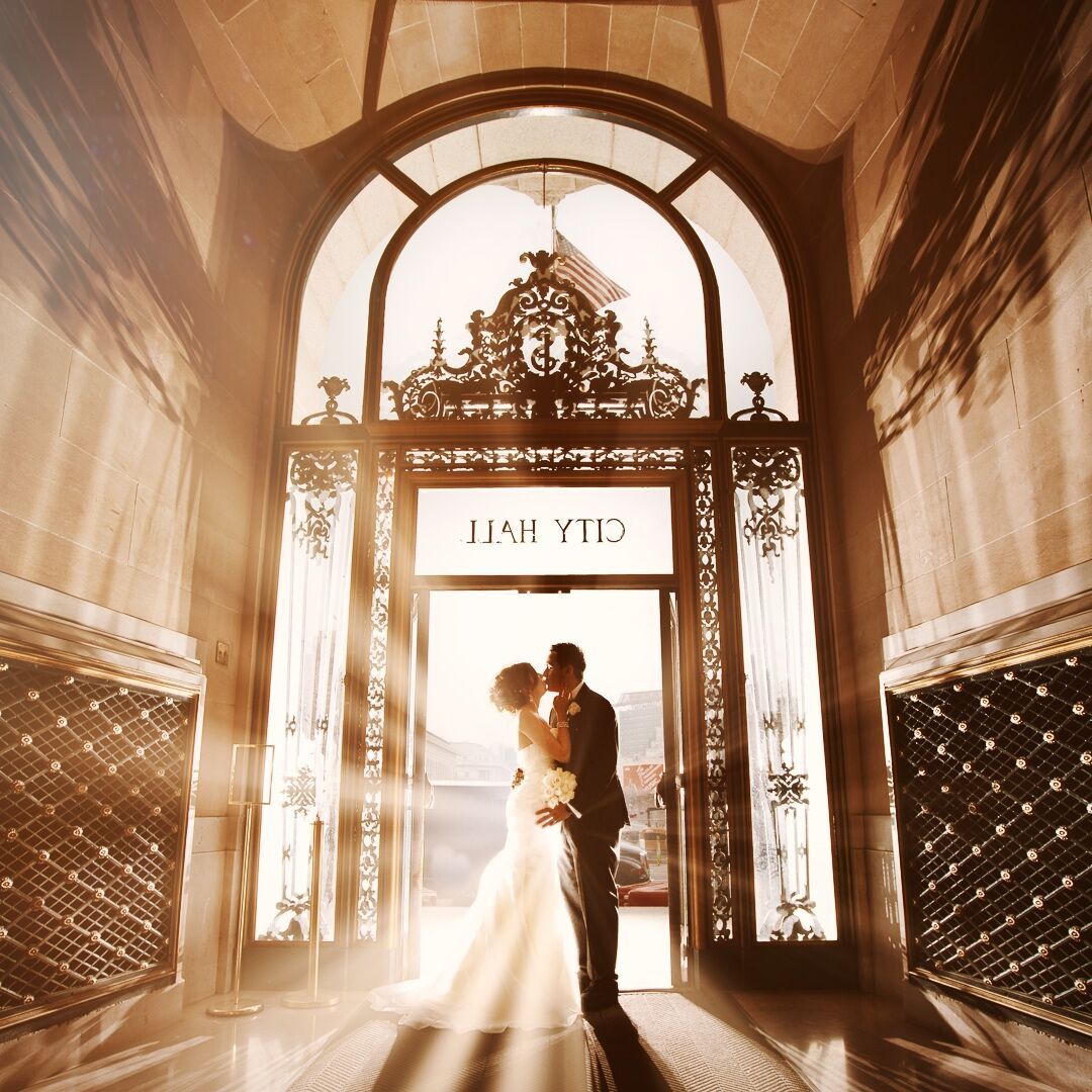 A bride and groom kissing at a doorway entrance of a city hall