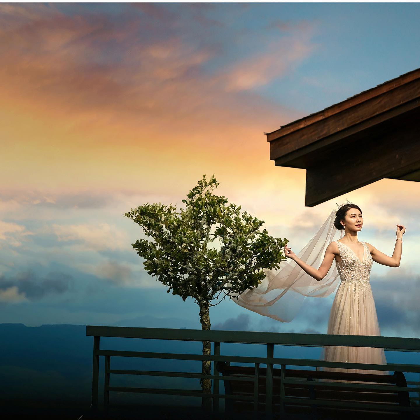 A bride standing at a balcony while posing with her veil during the blue hour