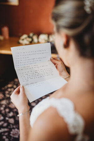 An over the shoulder shot of a bride reading a letter from the groom