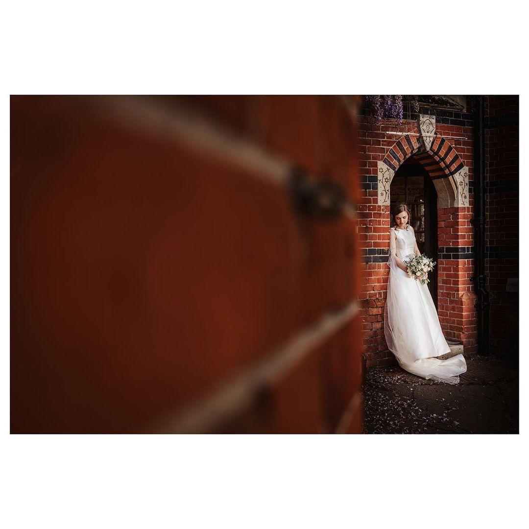 woman standing in a red brick archway wearing a wedding dress