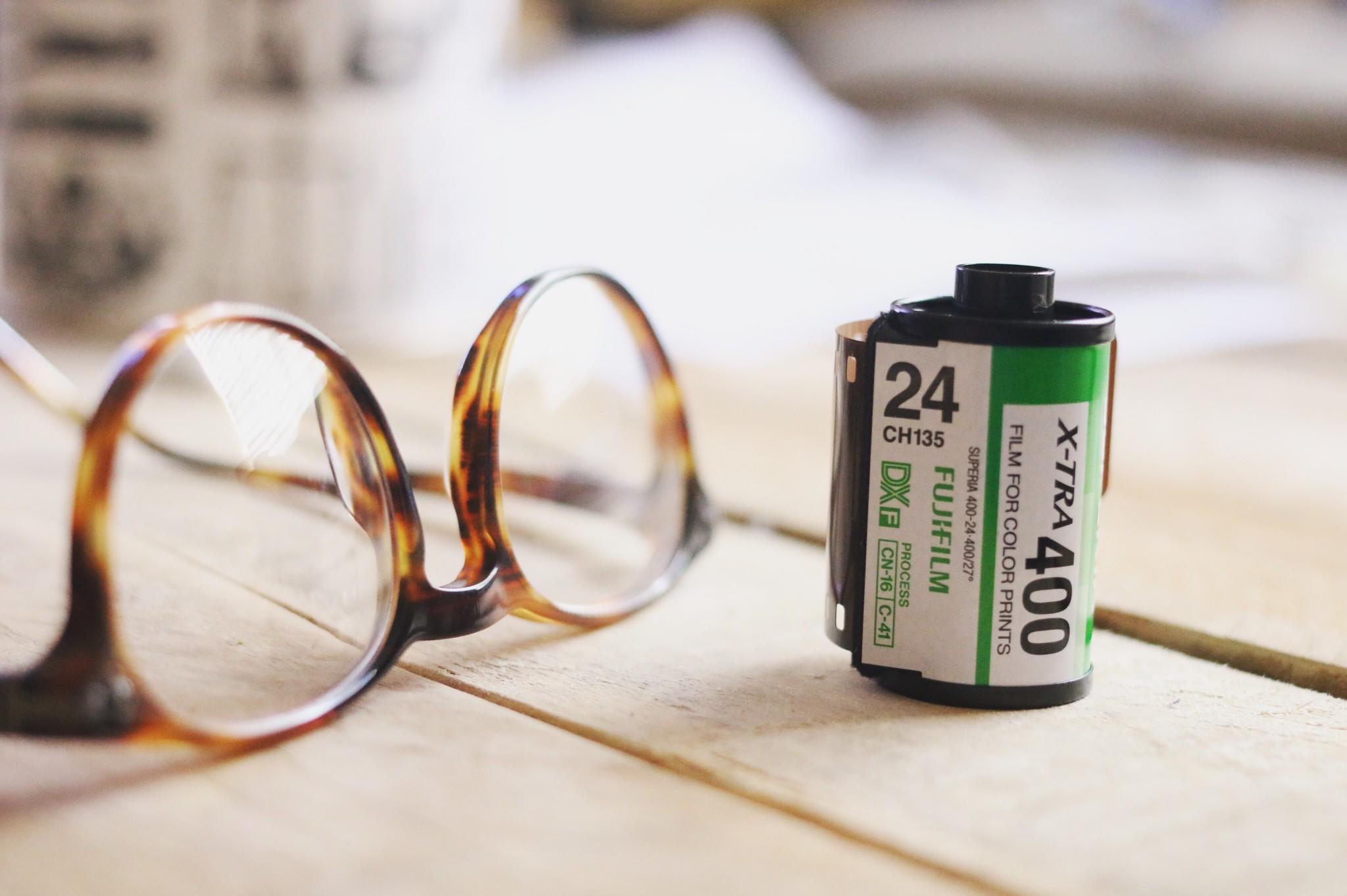 fuji 400 film cannister next to glasses on wood table