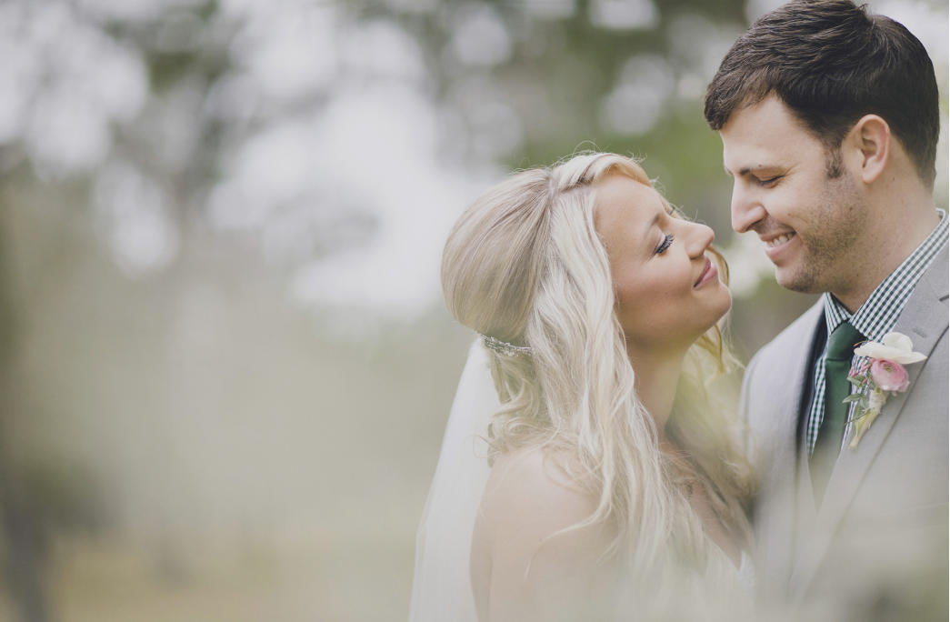 woman wearing veil and man in suit staring at each other smiling on their weddings day