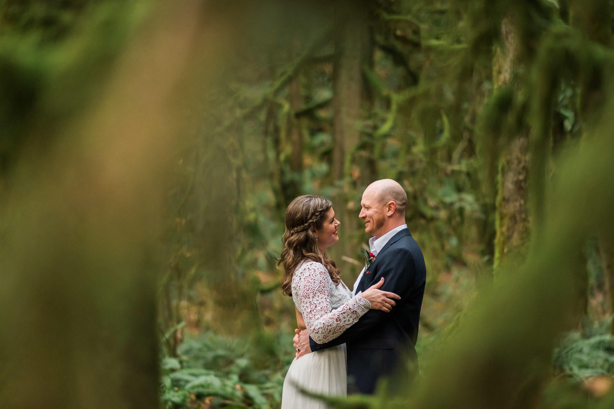 bride and groom looking at each other in a dense green forest