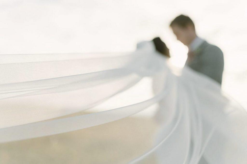 a intentional blurry image of a couple looking at each other while the bridal veil floats in air