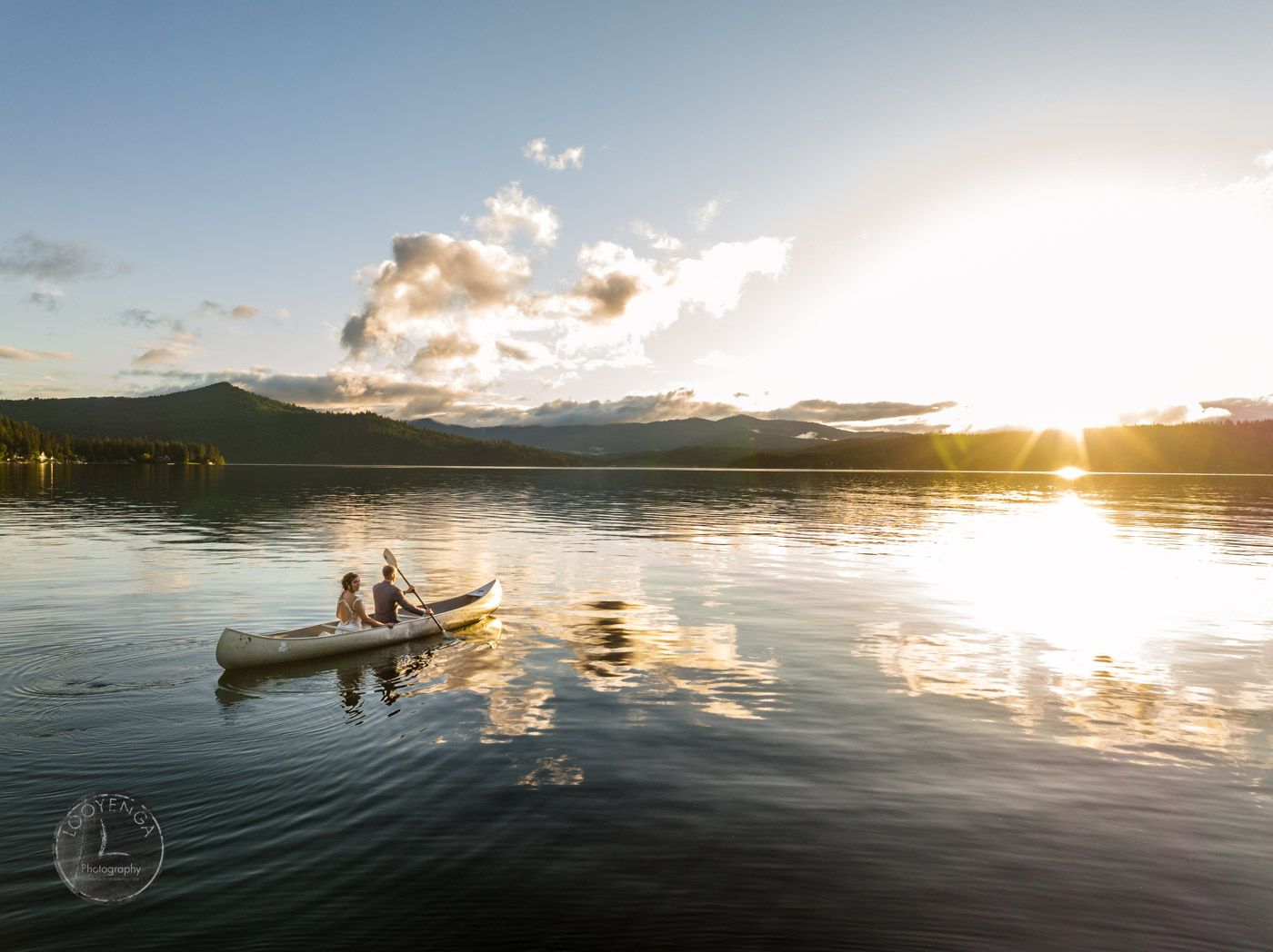 a wedding couple in a boat in the middle of a beautiful lake