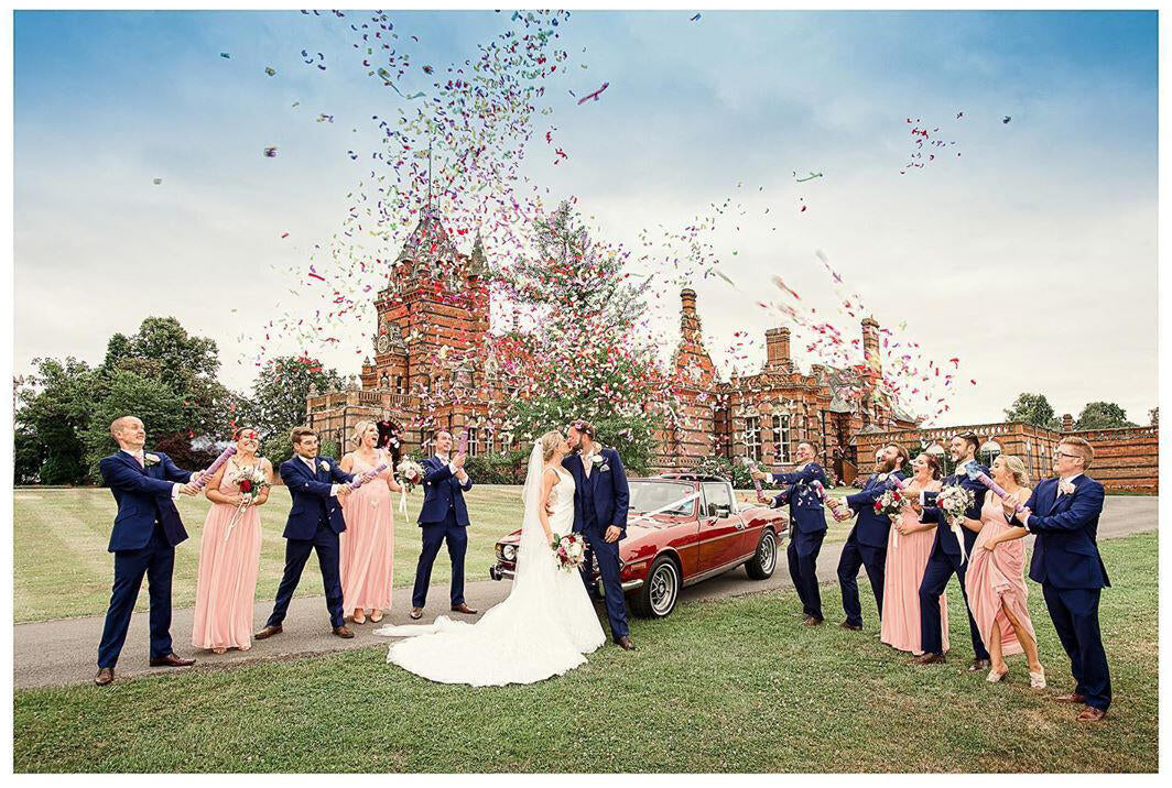 bridal party photos with bridal party throwing confetti and a classic car near a castle