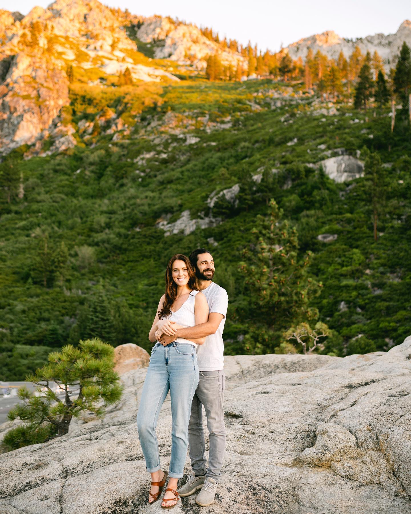 a groom holding the bride from behind and posing on a rocky terrain