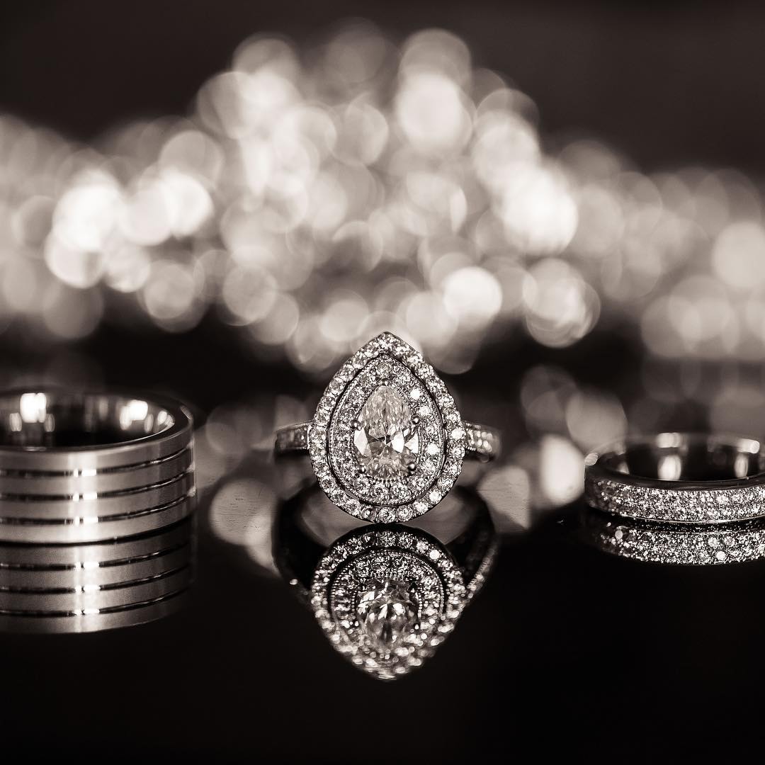 Detail photo of three wedding rings placed on a black reflective surface with a bokeh background 