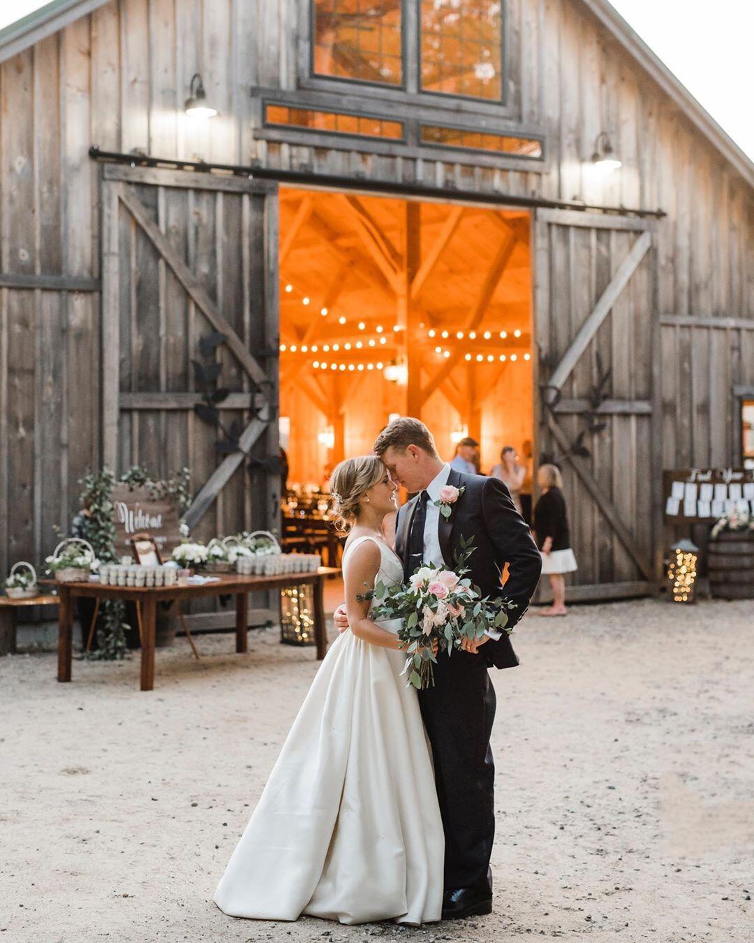 couple forehead to forehead at their wedding reception outside a barn