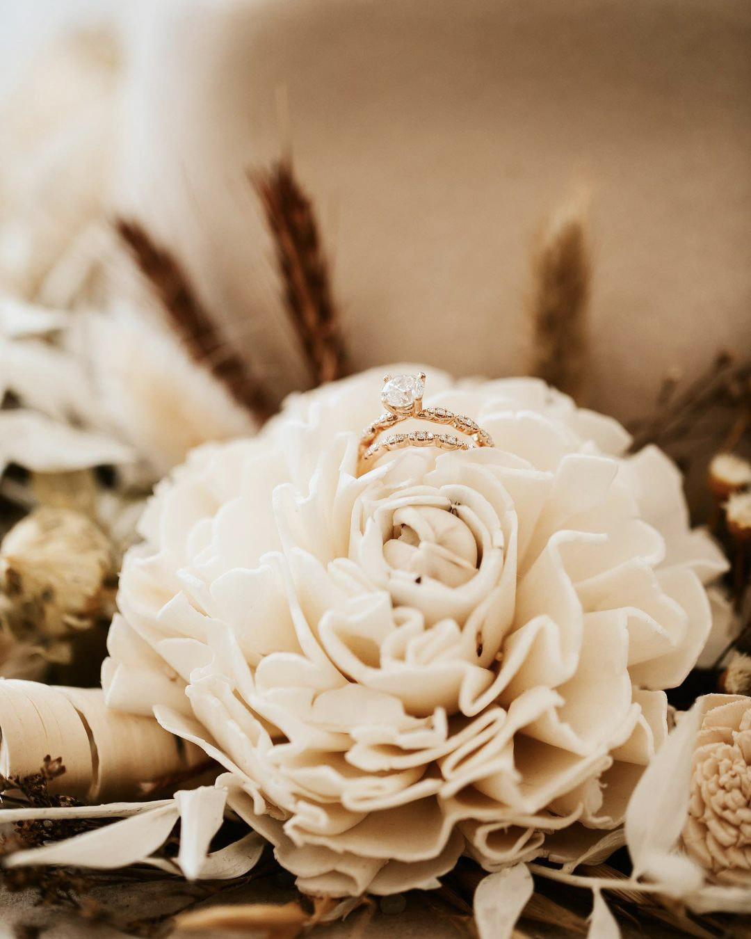 a wedding detail shot of the wedding ring on top of a flower