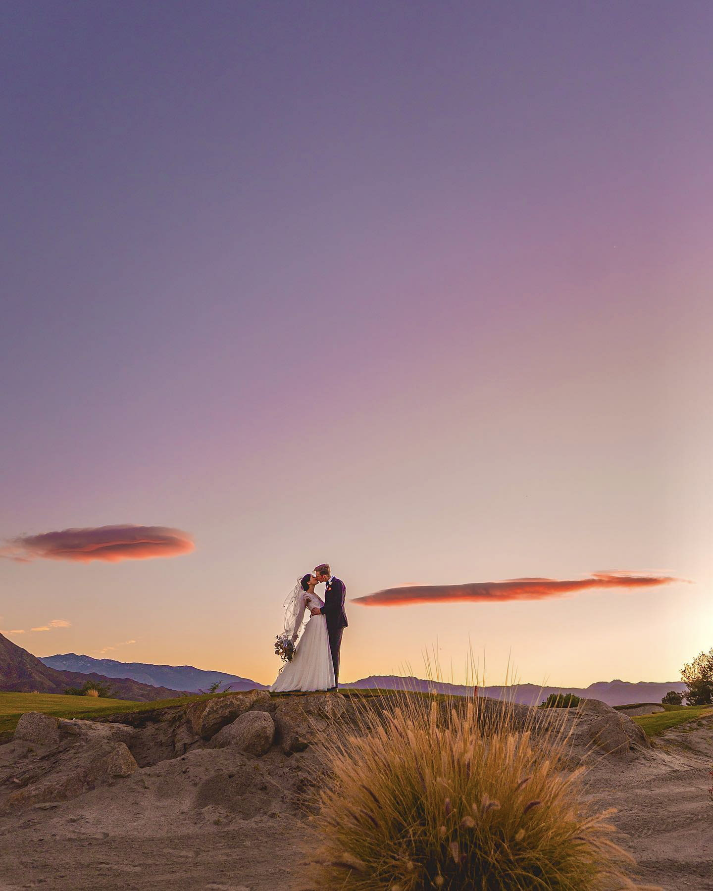 a wedding couple kissing with a beautiful sky in the background 