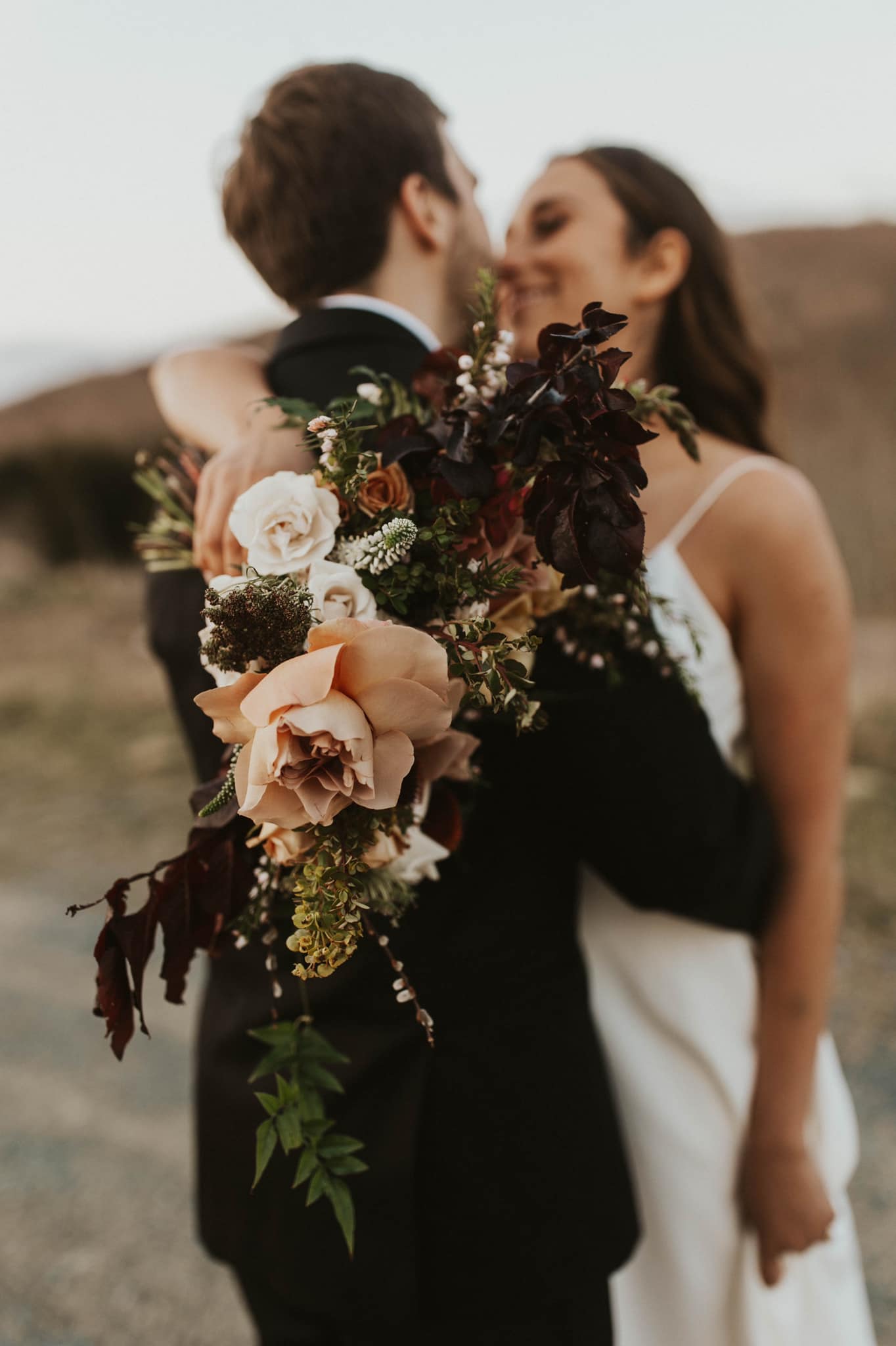 a wedding couple sharing a intimate moment with the bride holding the wedding bouquet