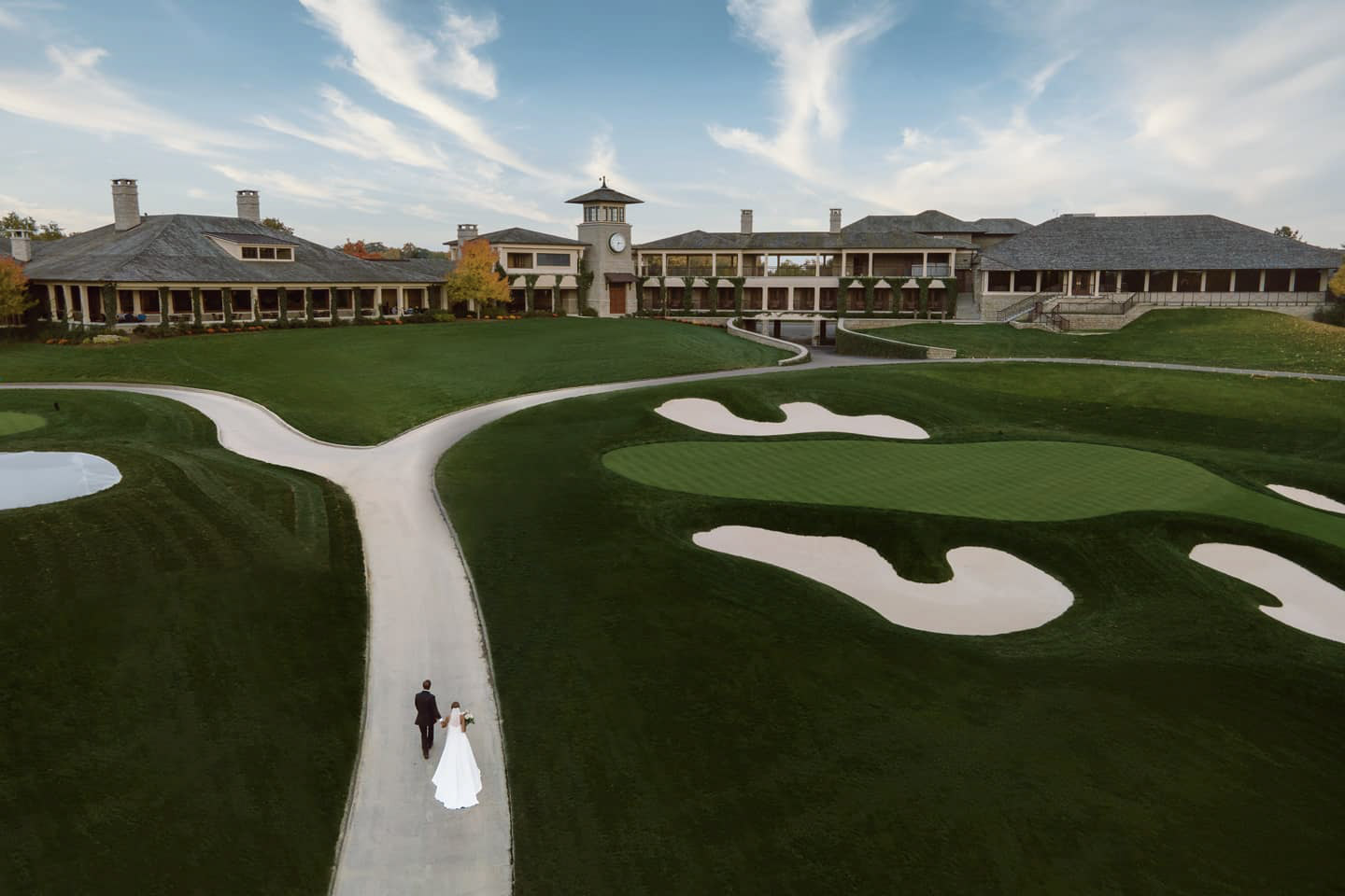 an aerial shot of the wedding couple walking through a golf course