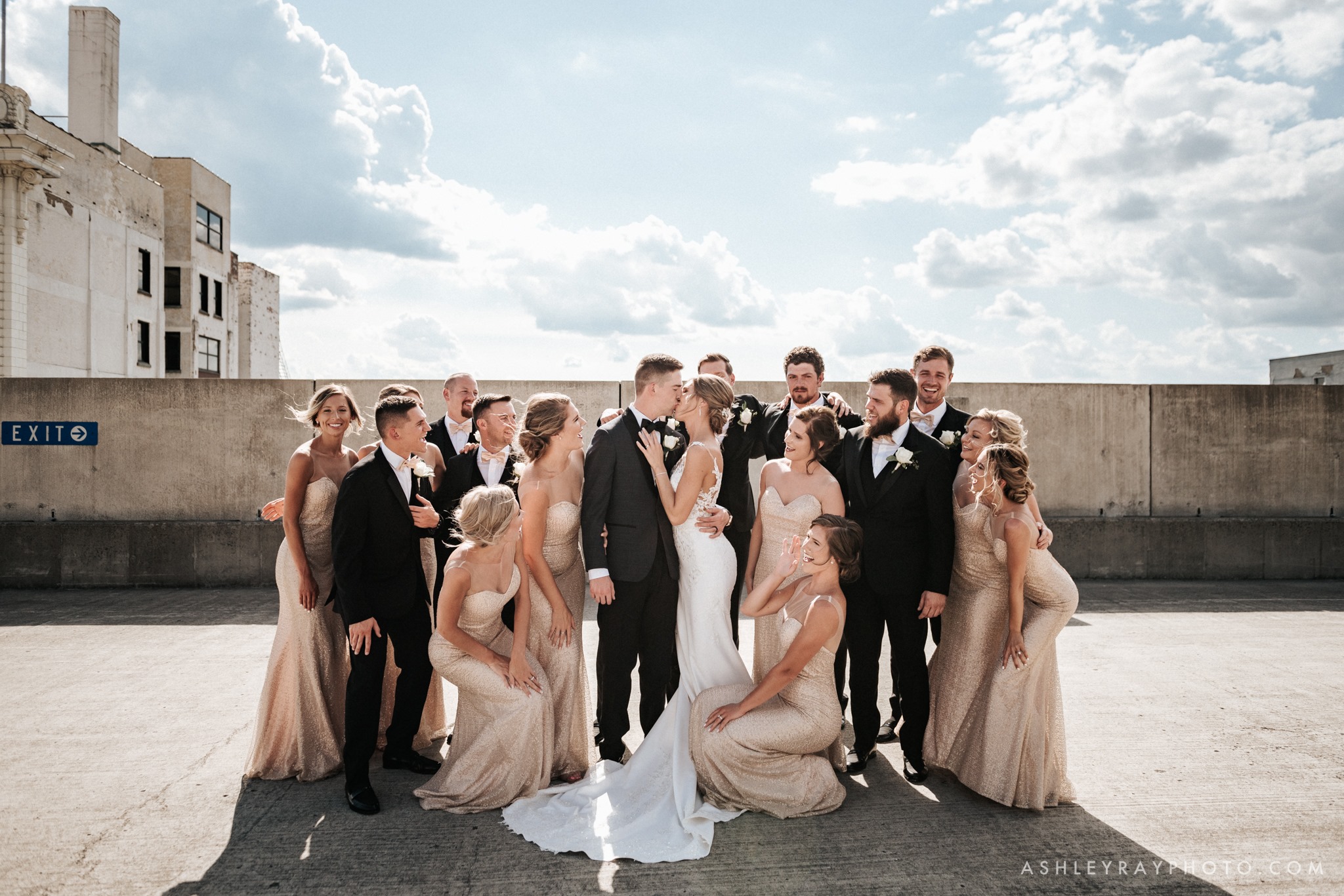 A bride and groom kissing as the bridesmaid and the groomsmen surround them