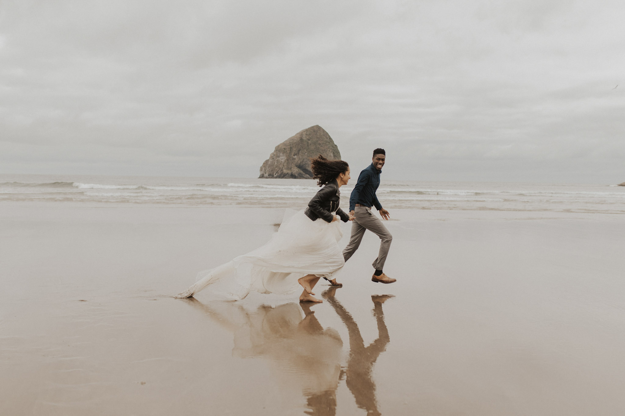 a couple running on the beach holding hands