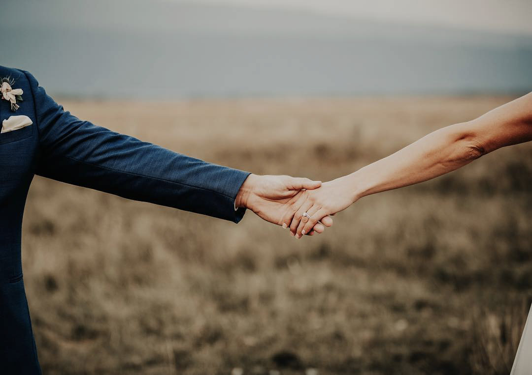 a couple holding hands while the wedding ring is visible 