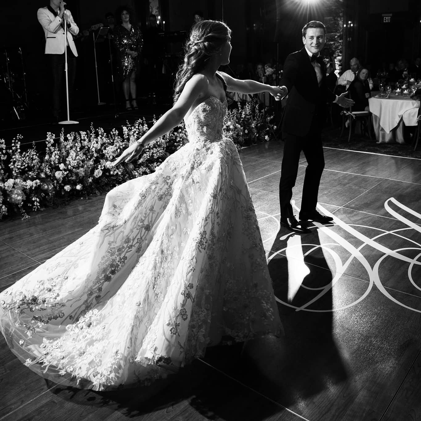 A bride and groom on the dance floor during their first dance as the band sings at the background