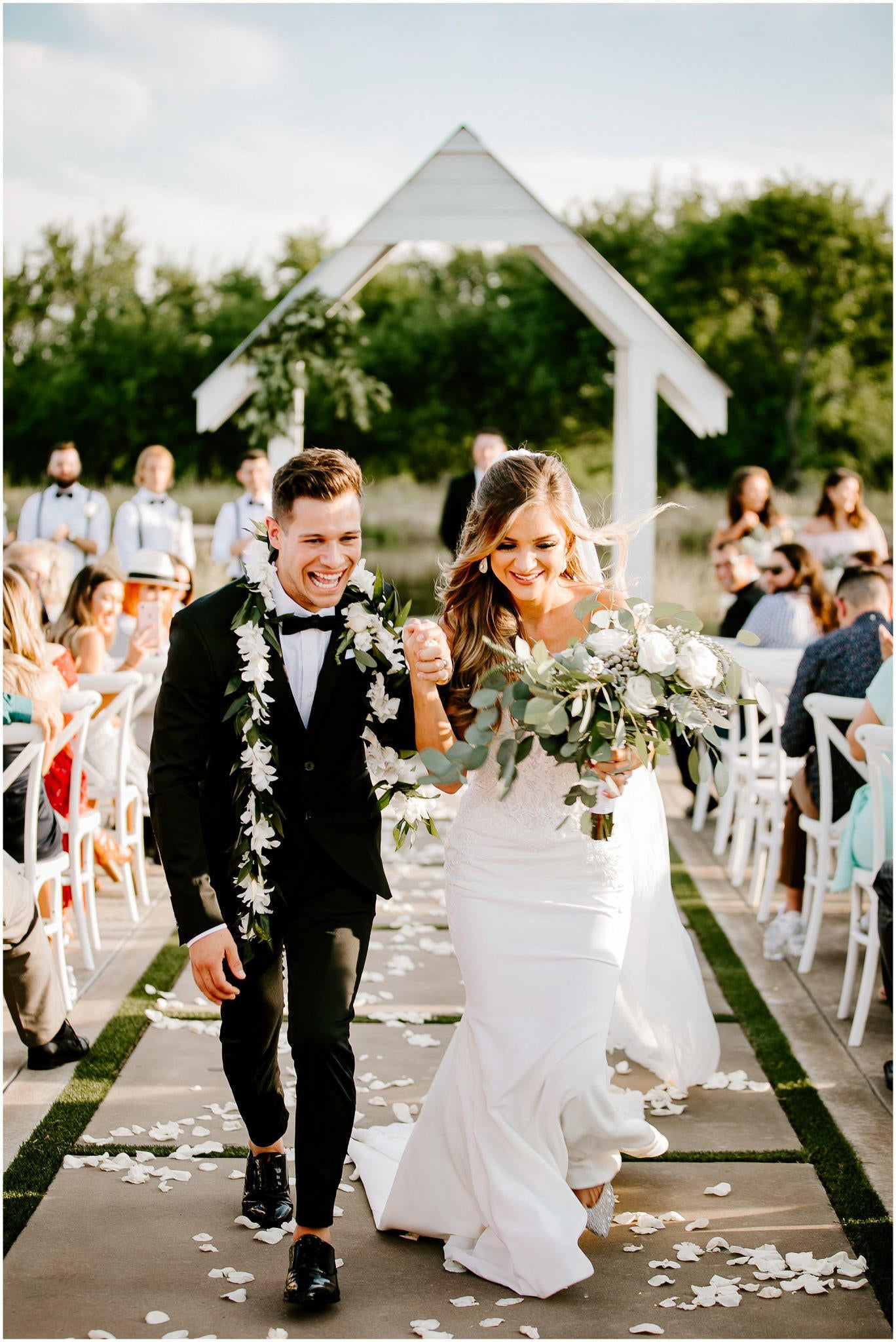 couple walking down aisle after ceremony in outdoor setting wearing leas