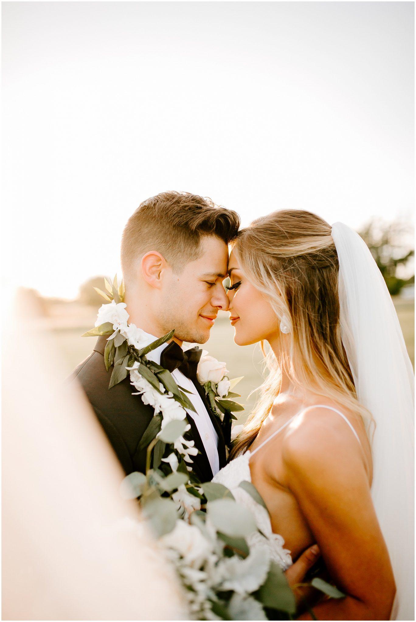 bride and groom nose to nose at sunset with flowers