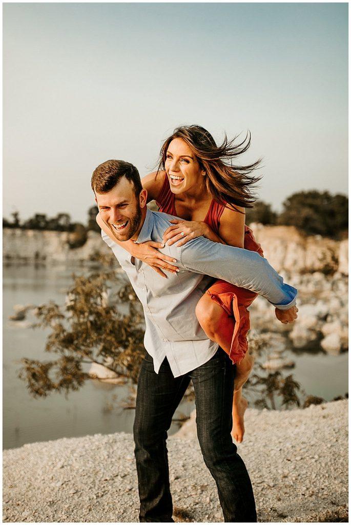 woman getting a piggyback ride from man while laughing near water by Brandi Allyse Photography