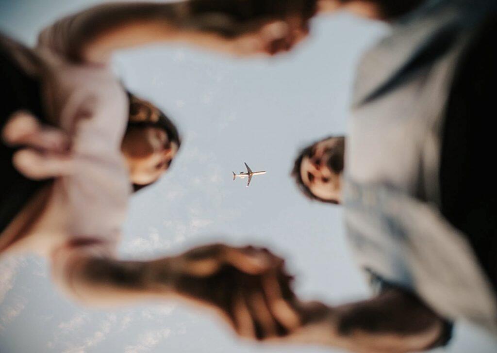 a mole's eye view of couple holding hands and a airplane can be seen between them 