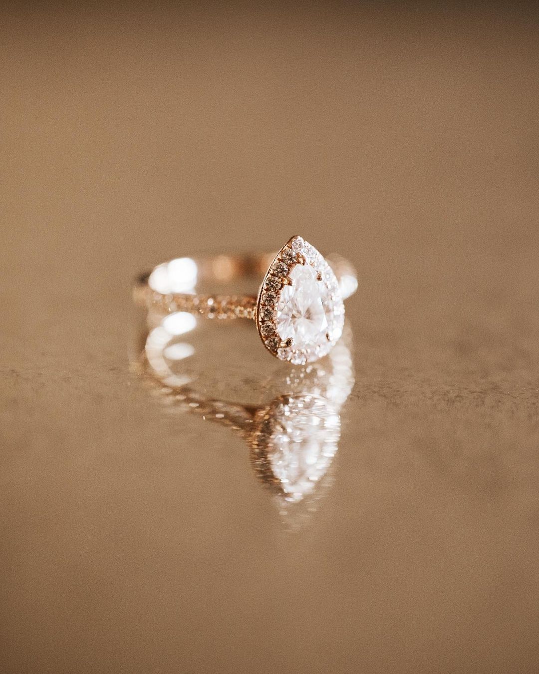 A pear-shaped wedding ring placed on a reflective surface 