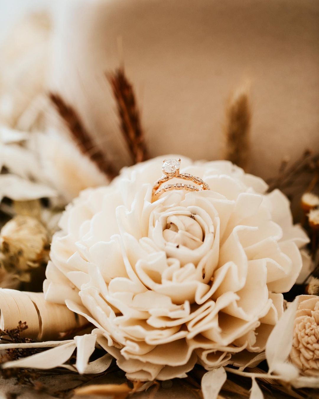 Close up shot of a wedding ring placed on top of an artificial white color flower