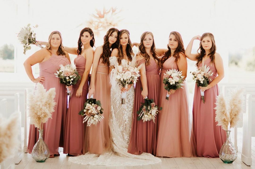 A bride posing with her bridesmaids holding the bridal bouquets